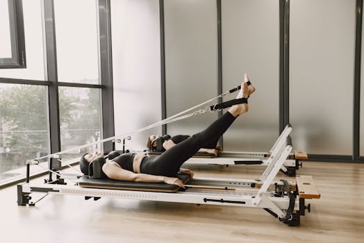 A woman working out on a pilates reformer machine in a modern gym setting.